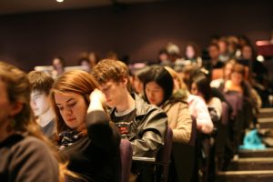 A group of students in a large lecture hall